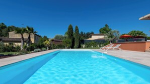 A rectangular swimming pool with clear blue water, surrounded by a concrete deck.