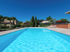 A rectangular swimming pool with clear blue water, surrounded by a concrete deck.