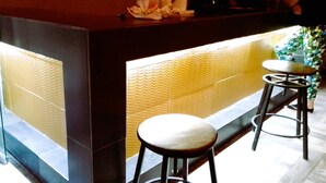 A reception area with a counter, two stools, and a patterned wall. - A04 SUPER SUITE PREMIUM AT PLAZA ACEQUIA (Cuautitlan Izcalli)