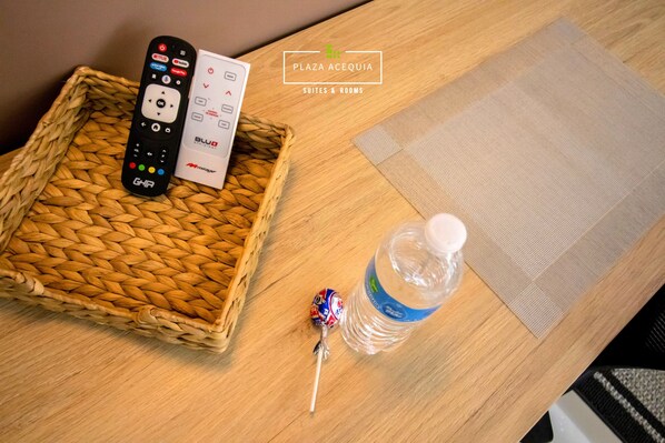 Un control remoto, una paleta y una botella de agua sobre una mesa de madera.