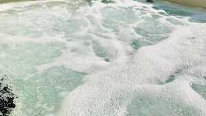 Een bubbelbad met uitzicht op bomen en een hangmat op de achtergrond.