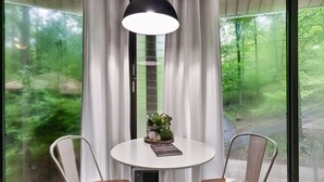 Een kamer met een ronde tafel, twee stoelen, een bloempot en een boek.
