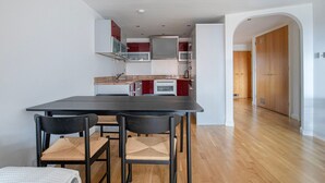 Una cocina moderna con comedor, que presenta una mesa y sillas oscuras, y piso de madera.