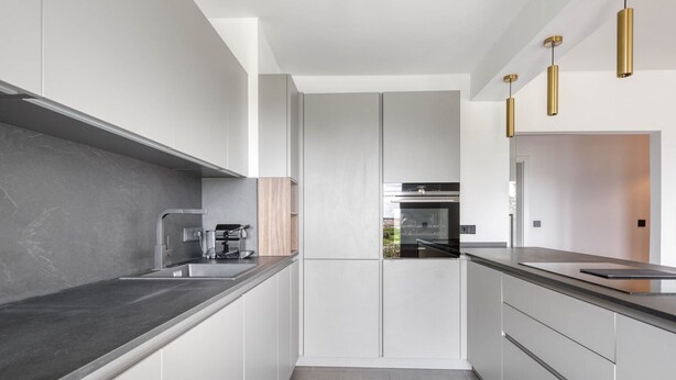 A modern kitchen with a central island, built-in appliances, and pendant lighting.