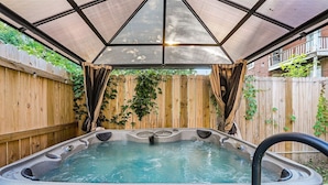 A hot tub with a canopy, surrounded by wooden fences and greenery. - Modern Luxury Retreat |Pet-Friendly |Hot Tub |BBQ (St. Louis)