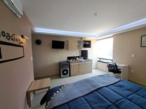 A compact hotel room with a kitchenette, a bed, a desk, and a TV. - A05 SUPER SUITE PREMIUM AT PLAZA ACEQUIA (Cuautitlan Izcalli)