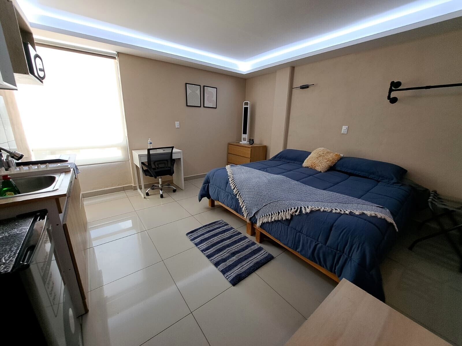 Un dormitorio con cama, mesita de noche, lámpara y escritorio con silla.
