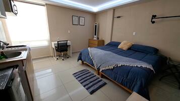 Un dormitorio con cama, mesita de noche, lámpara y escritorio con silla.