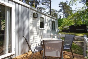 Une petite cabane avec une terrasse, une table et deux chaises.