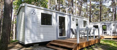 A white mobile home with a deck, a window, and a door.