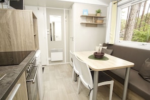 Cocina compacta con comedor, estufa integrada y ventana con vista a árboles.