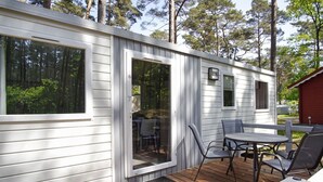 A mobile home with a deck, a dining table, and chairs. - Kleines Aber Feines Ferienhäuschen in Strandnähe - Tiny Chalet Nr. 816 - Tiny Chalets (Binz)