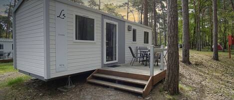 Ett husvagn med en veranda, ett bord och stolar.