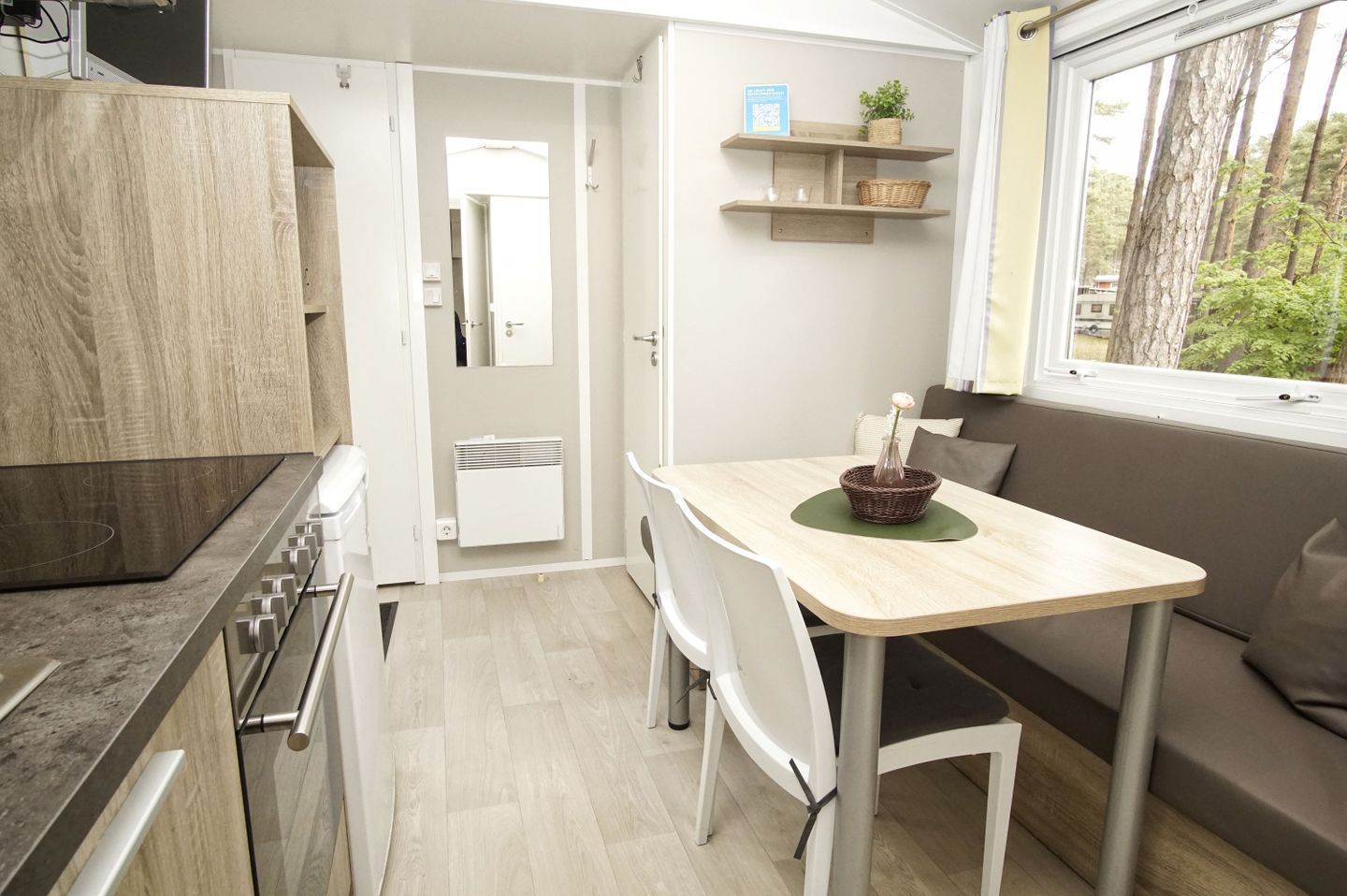 A compact kitchen with a dining area, a built-in stove, and a window with a view of trees.