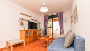 A small, cozy room with a wooden bench, a small table, a sofa, and a TV. - OASIS PLAYERO - Nice flat with shared pool and Free Wifi (Chiclana de la Frontera)