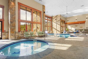 Un espace piscine intérieure comprenant plusieurs bassins, des murs en pierre et des poutres en bois.