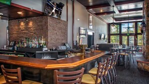 Un espace bar avec un mur en pierre, un comptoir en bois et de nombreux tabourets de bar.