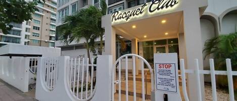 A building entrance with a sign reading "Racquet Club" and a white gate with a stop sign.