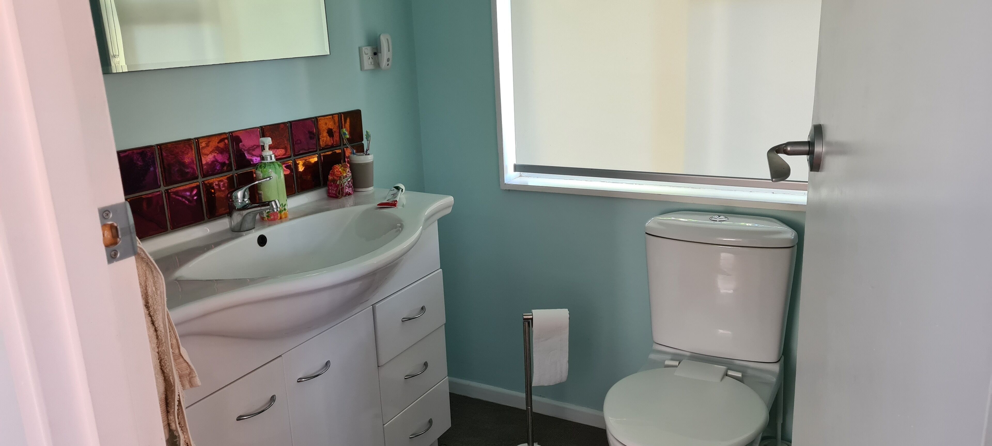 A bathroom with a white sink, a toilet, and a window.