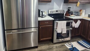 A kitchen with stainless steel appliances, wooden cabinets, a stove, and a toaster.
