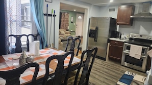 A compact kitchen with a refrigerator, stove, and microwave. There is a dining area with a table and chairs.