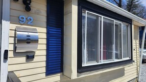 A mobile home with a number '92' on the side, a blue door, and a window with a black frame.