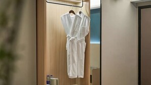Un armario de madera con dos albornoces blancos colgados en una barra.