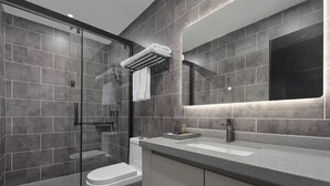 Un baño moderno con cabina de ducha de vidrio, inodoro blanco y encimera con lavabo y espejo.