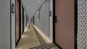 Un pasillo de hotel con paredes estampadas, puertas y suelo alfombrado.