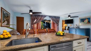 Eine Küche mit Granit Arbeitsplatten, Edelstahlgeräten und einem Essbereich mit Holztischen und einem Tisch.