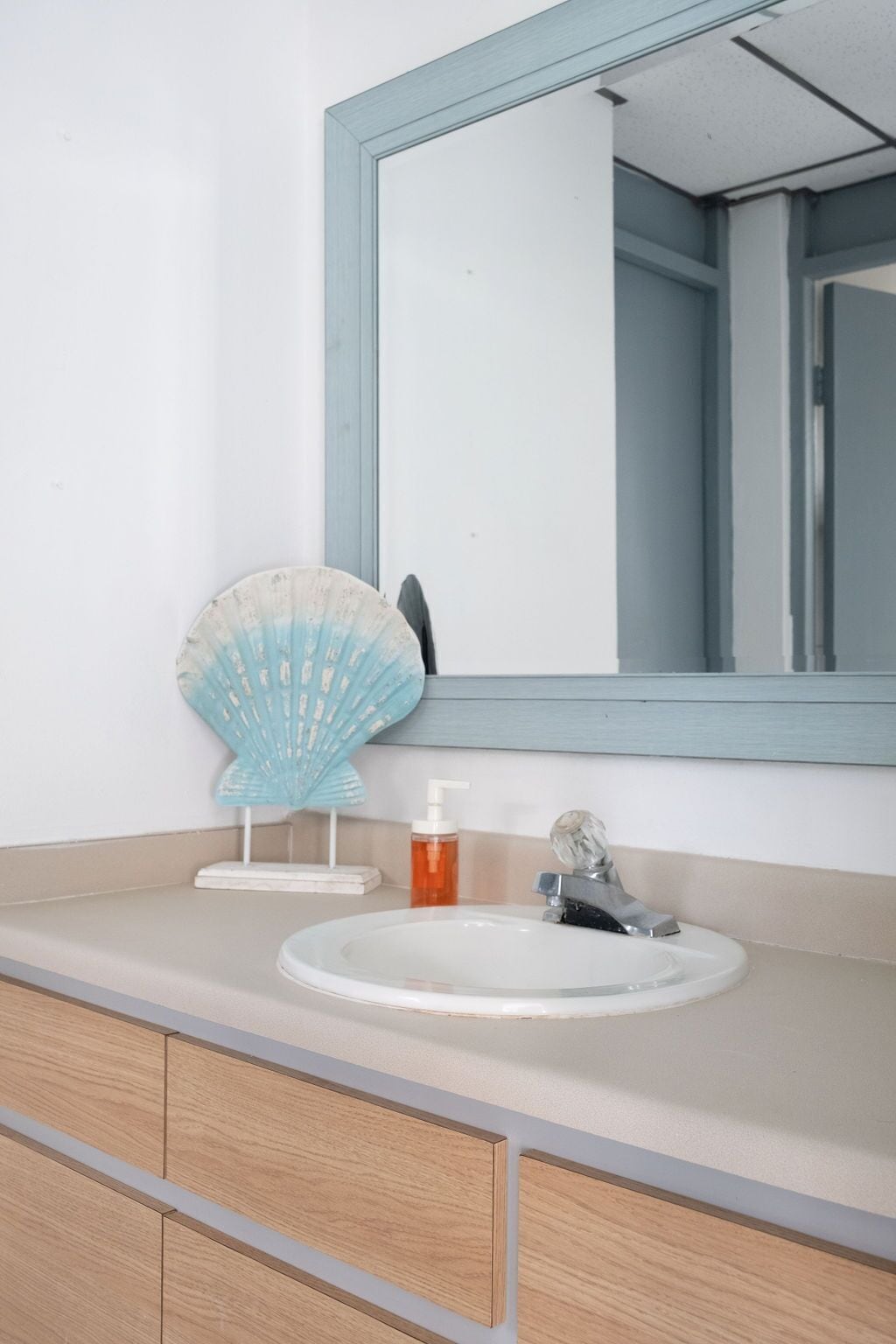 A bathroom with a white sink, a mirror, and a wooden vanity.