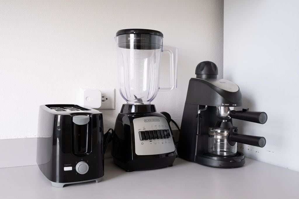Een keukentafel met een broodrooster, een blender en een koffiezetapparaat.