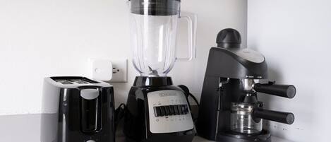 Un plan de travail de cuisine avec un grille-pain, un mixeur et une machine à café.