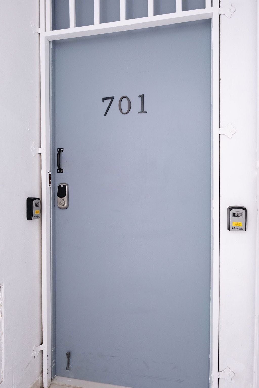 Une porte portant le numéro 701, un système de verrouillage à clavier et une sonnette fixés sur un mur blanc.