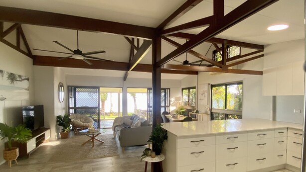 Amplia sala de estar con una isla grande, ventilador de techo y vistas al exterior.