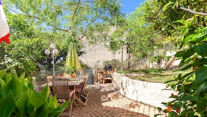 An outdoor patio area with a brick floor, wooden furniture, and a grill. - Villa 'Familidy' with Private Pool, Wi-Fi and Air Conditioning (Bandol)