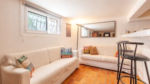 A room with two white sofas, a black bar stool, a large mirror, and a window with blinds. - Villa 'Familidy' with Private Pool, Wi-Fi and Air Conditioning (Bandol)