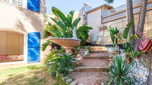 A garden with a stone pathway, a blue door, and a hammock. - Villa 'Familidy' with Private Pool, Wi-Fi and Air Conditioning (Bandol)