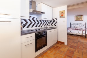 Cozinha com armários brancos, forno preto e backsplash em padrão herringbone.