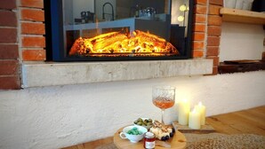 A cozy room with a fireplace, a small table with snacks and drinks, and a window overlooking the fire. - Holiday Home 'Casa Storica Gardola' with Lake View, Wi-Fi and Air Conditioning (Tignale)
