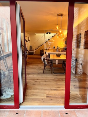 Un intérieur moderne avec un plancher en bois, un escalier, un coin repas et une cuisine.