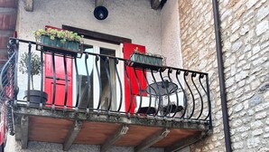 A two-story building with a balcony, a red door, and a stone wall. - Holiday Home 'Casa Storica Gardola' with Lake View, Wi-Fi and Air Conditioning (Tignale)