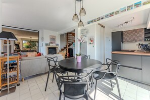 Eine moderne Küche mit Essbereich, einer Treppe und einem Wohnzimmer mit Sofa und Fernseher.
