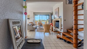 A spacious living area with a large window, a wooden staircase, and a television.