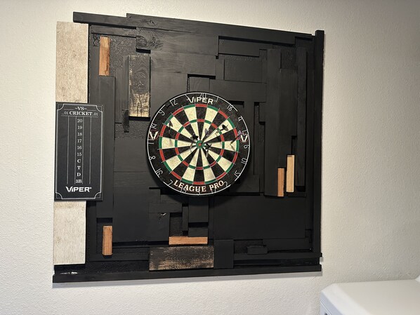 A dartboard mounted on a wall with a scorecard to the left.