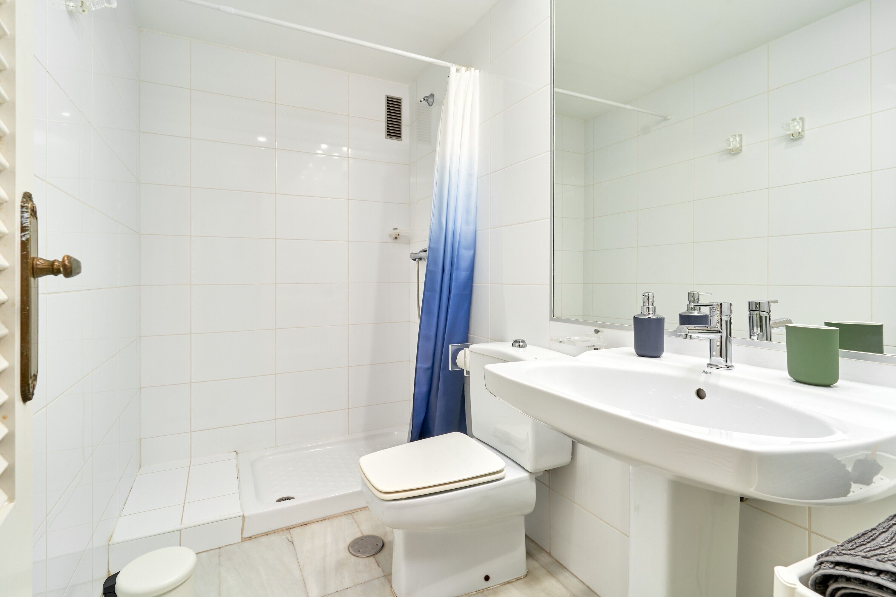 A bathroom with a shower, toilet, sink, and mirror.