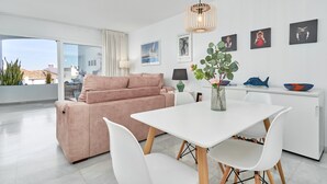 Una sala de estar moderna con sofá, mesa de comedor, sillas y obras de arte en las paredes.
