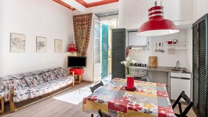 A compact living space with a sofa, a dining table, a kitchen area, and a television. - Apartment 'Piter' with Private Terrace (Bonassola)