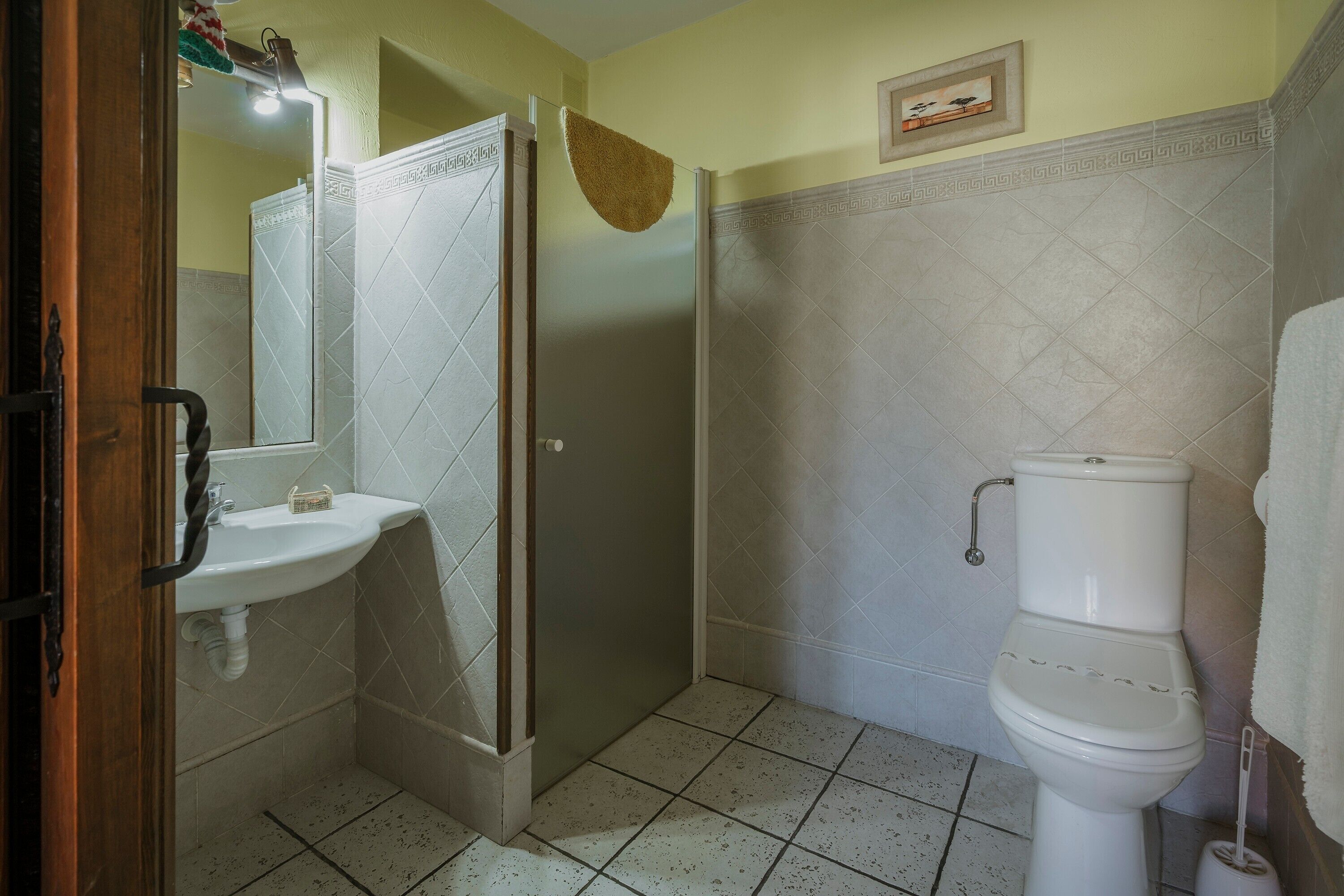 Un baño con ducha, lavamanos, inodoro y piso de baldosas.