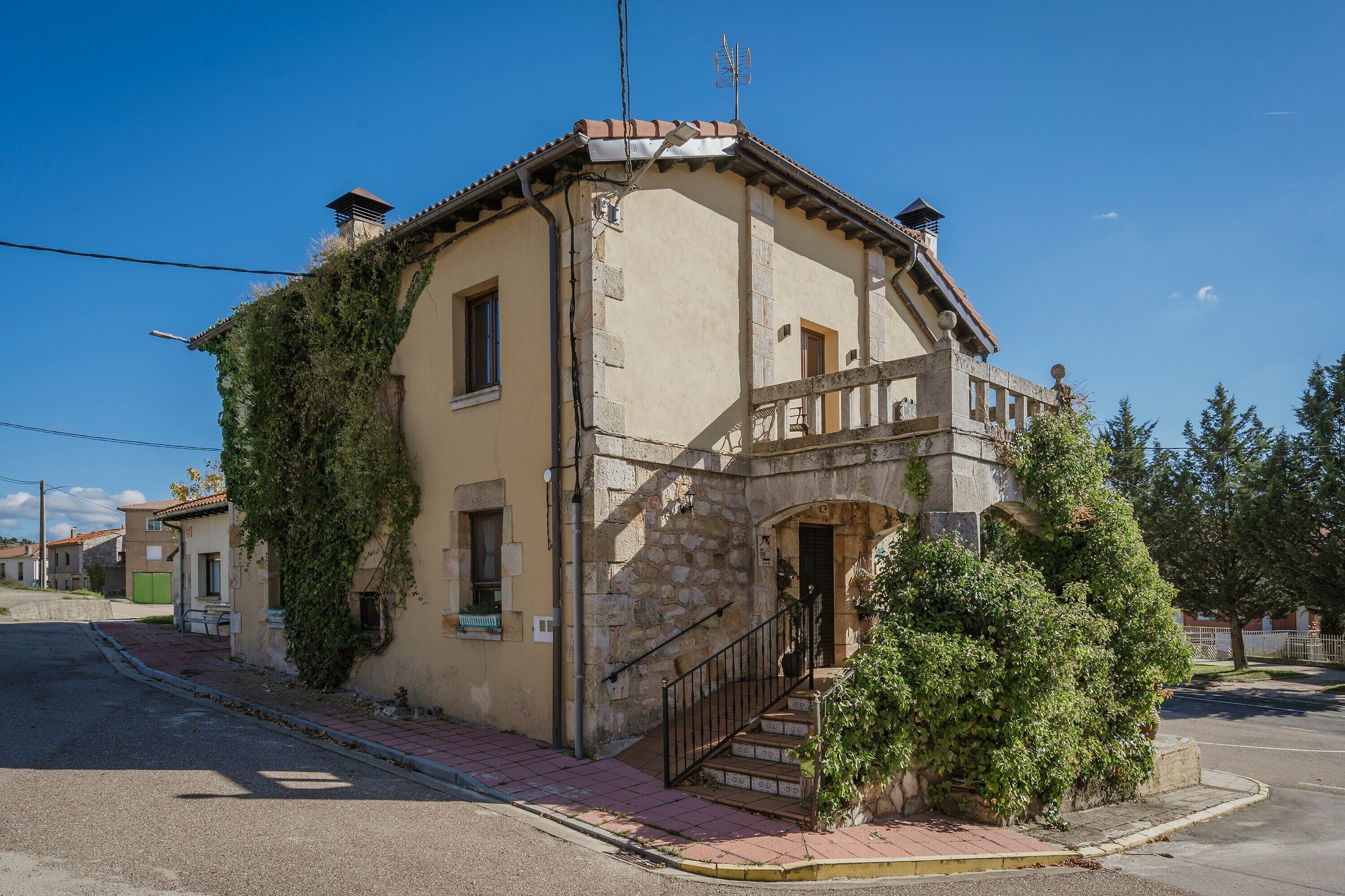 A two-story building with a stone facade, a balcony, and a staircase leading to the entrance.